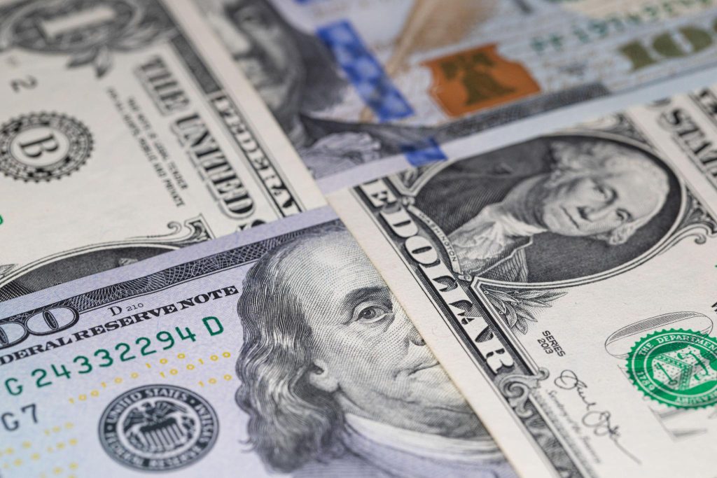 Close-up of overlapping U.S. hundred-dollar bills, with Benjamin Franklin’s portrait visible on the foreground note.