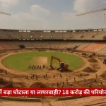 A large stadium under construction with two tall cranes and workers on the field.