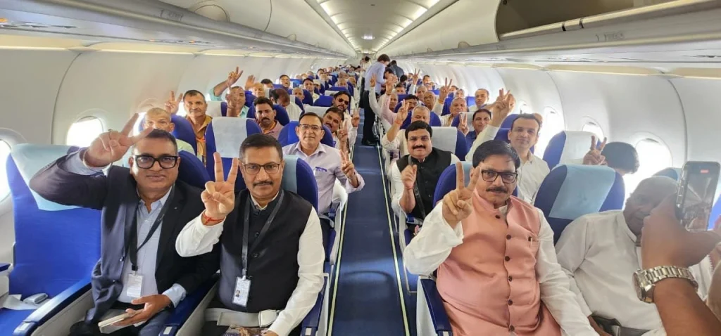 HK037JNbIAEr7O6 - The Journalist News Large group of passengers in an airplane cabin posing for a group photo, many showing two-finger V-signs.