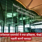 Noida International Airport terminal with glass façade; red Hindi news banner proclaims historic first cargo flight, The Journalist News logo top-right.