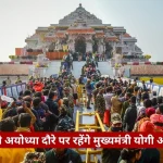 Crowd gathers at a temple complex with steps leading to a carved shrine, people taking photos and soldiers nearby; a red banner spans the bottom with Hindi text.