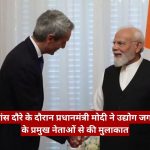 Two men in formal attire shake hands in a room, with a red Hindi news banner across the bottom and a flag in the background.