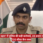 Indian police officer in khaki uniform and beret sits at a desk with Indian flag behind him, during a news briefing.