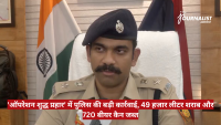 Indian police officer in khaki uniform and beret sits at a desk with Indian flag behind him, during a news briefing.