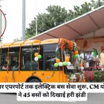 Ceremonial launch of 100% electric bus service with a decorated orange bus, stage, crowd, Indian flags, and a circular inset portrait of a man in saffron robes.