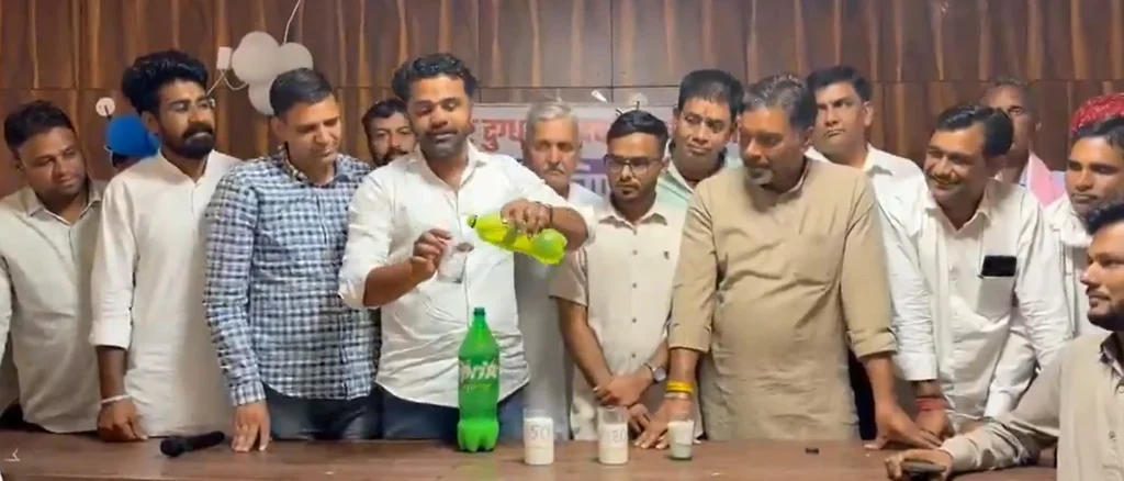 Screenshot 2026-06-24 160011 - The Journalist News Group of men around a table as one pours a bright green drink from a bottle into a cup in a celebratory setting