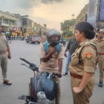 Group of police officers standing and talking to a helmeted motorcyclist at a busy city intersection during daytime.
