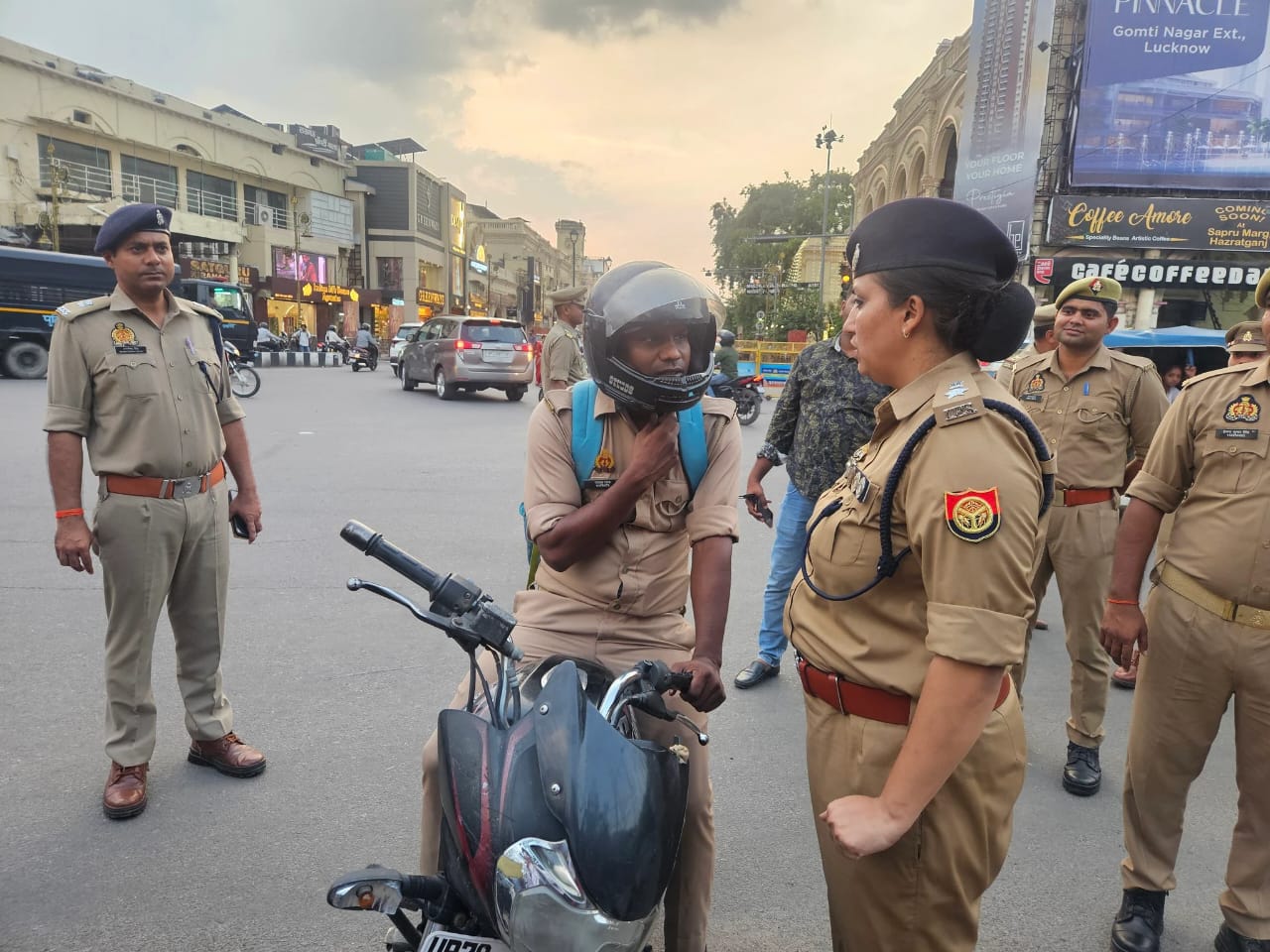 Group of police officers standing and talking to a helmeted motorcyclist at a busy city intersection during daytime.
