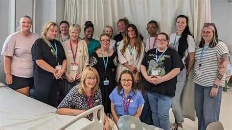 Group of diverse healthcare staff and volunteers posing for a photo in a hospital ward.