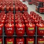 Rows of red LPG gas cylinders labeled 5 kg on warehouse shelves in storage racks.
