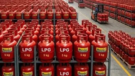 Rows of red LPG gas cylinders labeled 5 kg on warehouse shelves in storage racks.