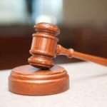 Judge's gavel resting on a wooden sound block on a courtroom desk, symbolizing a court ruling or legal decision.