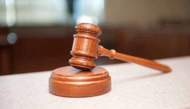 Judge's gavel resting on a wooden sound block on a courtroom desk, symbolizing a court ruling or legal decision.
