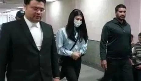 WhatsApp Image 2026-06-03 at 112822 PM - The Journalist News Three people walk down a hallway: a man in a suit on the left, a masked woman in the middle, and a man in a dark sweater on the right.