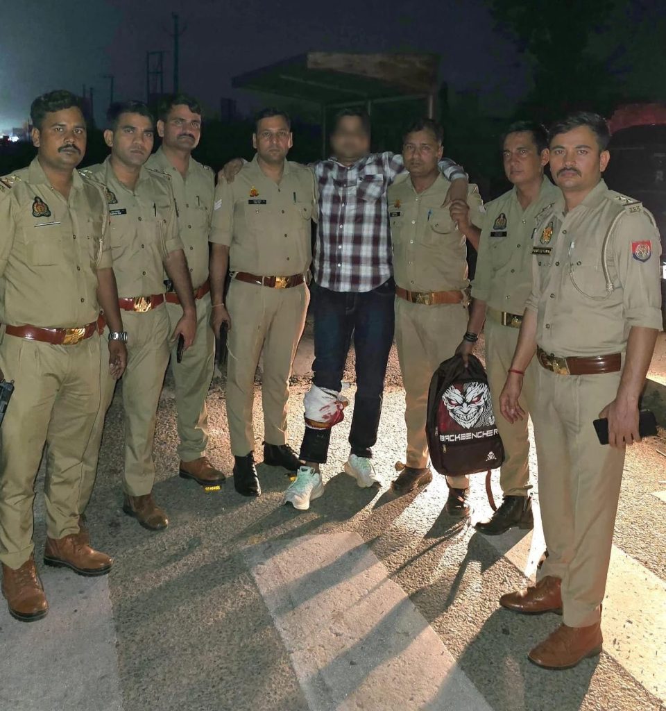 WhatsApp Image 2026-06-08 at 31648 PM 1 - The Journalist News Group of uniformed police officers posing with a man who has bandaged legs, standing on a road at night; a backpack with a Joker graphic is visible.