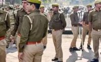 Group of uniformed officers standing in formation on a parade ground, some holding rifles, wearing yellow caps and brown belts.