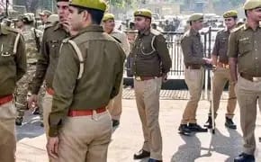 Group of uniformed officers standing in formation on a parade ground, some holding rifles, wearing yellow caps and brown belts.