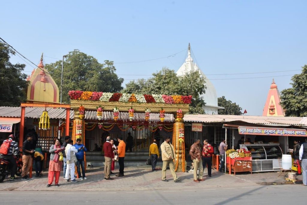 Temple entrance decorated with colorful flower garlands; people gather for a festival outside the shrine.