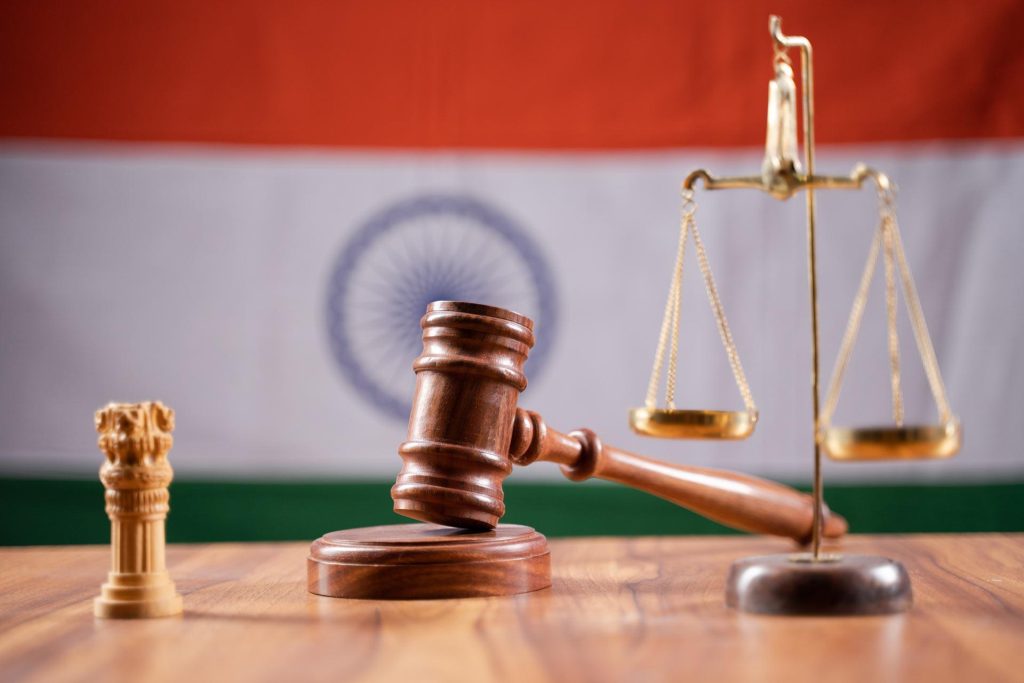 Gavel and scales of justice on a wooden desk with the Indian flag in the background, symbolizing law in India.