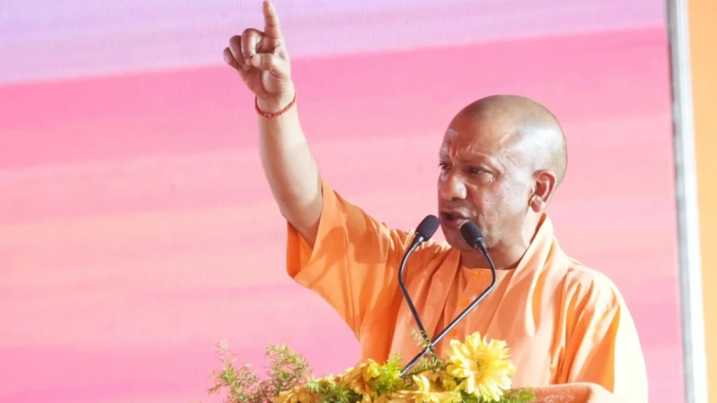 cm-yogi-adityanath_f637de42f61181e728d1cafb6f353754 - The Journalist News Man in an orange robe speaks at a podium, raising his right index finger as he makes a point.