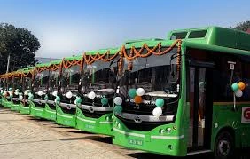 download 4 - The Journalist News Row of green buses lined up, decorated with orange garlands and balloons for a celebration on a sunny day.