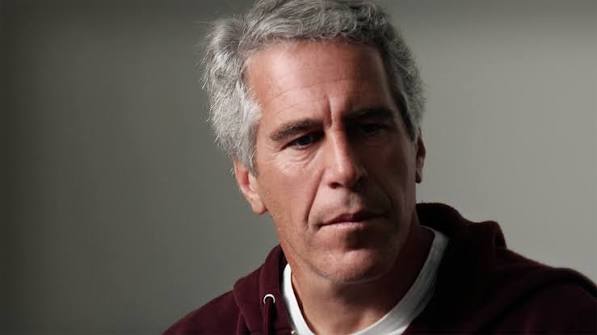 Close-up of a middle-aged man with gray hair wearing a maroon hoodie, looking thoughtful and downward.