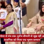 Woman in saree hands a ceremonial trophy to another woman in traditional dress as a man in uniform looks on in the background.