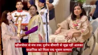 Woman in saree hands a ceremonial trophy to another woman in traditional dress as a man in uniform looks on in the background.