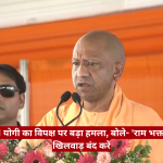 Bald man in orange robes speaks at a podium with two microphones; a man in sunglasses stands behind him; orange backdrop and a red Hindi headline banner across the bottom.