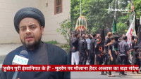 Male reporter in black attire with a turban speaks into an IANS microphone as a black-clad crowd participates in a procession behind him.