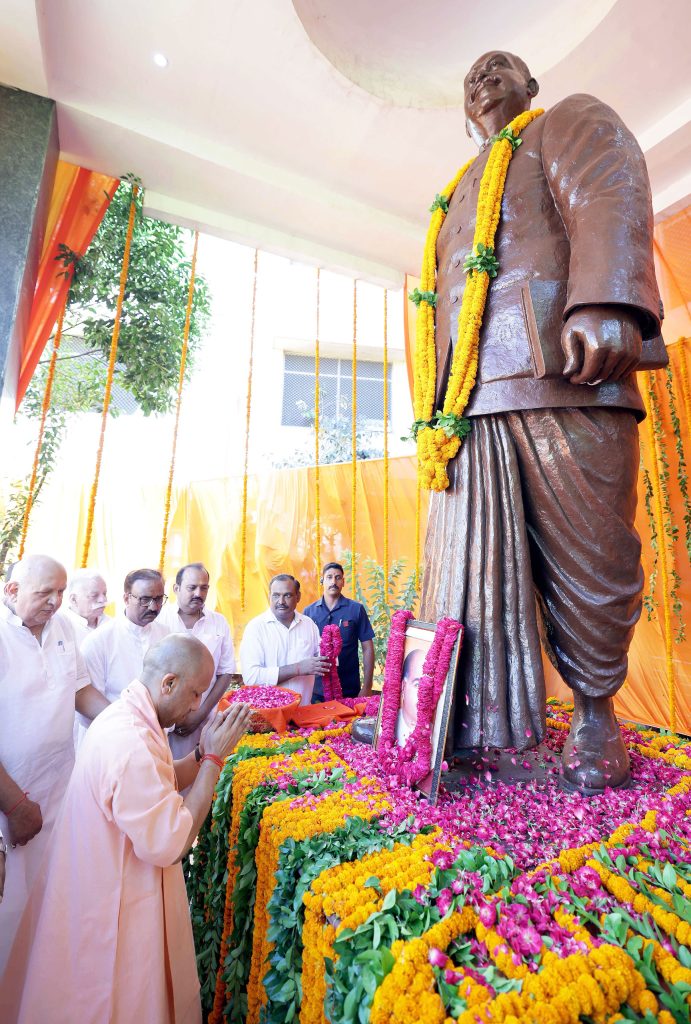 HMhPtvNaAAA4TnZ - The Journalist News Bronze statue wearing orange marigold garlands, surrounded by people praying and flowers at a ceremonial setup.