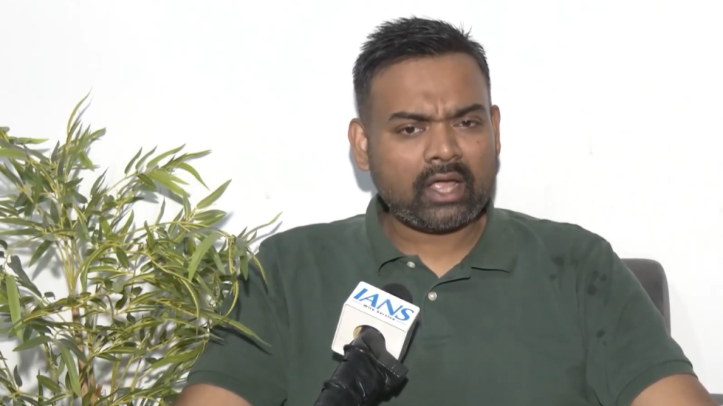 Light Blue and Yellow Bold Month Astrology Horoscope YouTube Thumbnail 22 - The Journalist News Man in a green polo shirt sits for an interview, speaking into a microphone labeled IANS with a potted plant beside him.