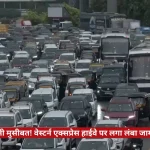 Heavy traffic on a Mumbai road with cars, buses, and motorcycles; red Hindi news ticker runs across the bottom.