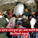 Crowd at a cave shrine offering prayers, with a white statue and a large red Hindi banner across the scene; news logo top right.