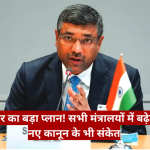 Indian official at a press conference speaking into a microphone, with the Indian flag on the table and a red Hindi headline banner across the bottom.