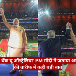 Two leaders raise their clasped hands in triumph on a stage in a packed stadium, Modi in a beige kurta beside a suited official.