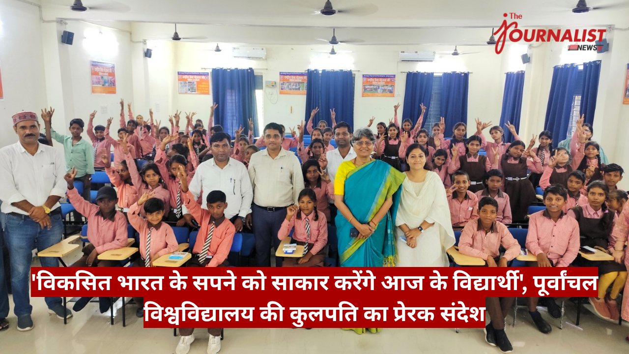 Group of students in pink shirts and brown uniforms posing in a classroom, many raising hands, with adults at the front and a red Hindi banner across the bottom.