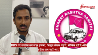 Male reporter in a white shirt speaks into a microphone during an interview, with a pink BRS emblem/logo on the right and a red Hindi news banner across the bottom left to right.